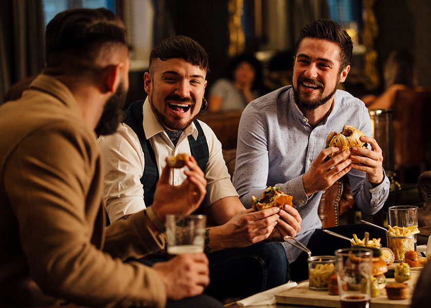 Happy men eating at restaurant