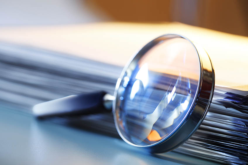 Magnifying glass leaning against a stack of financial documents.