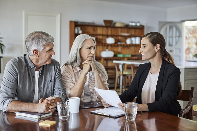 Mature couple meeting with a financial advisor at home, reviewing legacy and estate documents